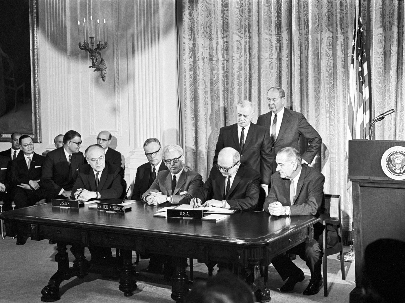 A black and white photograph of a group of men signing the Outer Space Treaty in 1967